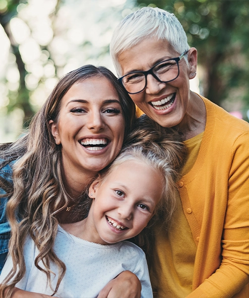 A girl with her mom and grandmother, all smiling.